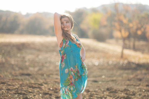 Heureuse jeune femme métissée en robe bleue pose dans le champ détruit par un feu de forêt alors qu'il est recouvert de cendres
 - Photo, image