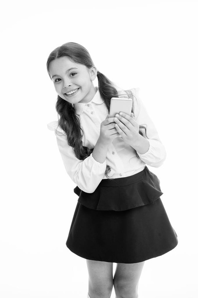 Girl cute long curly hair holds smartphone white background. Child girl school uniform clothes holds smartphone. Child school uniform smart kid happy face. Parental advisory concept. Always in touch - Foto, Bild