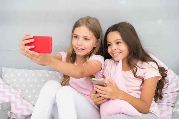 Online entertainment. Explore social network. Smartphone for entertainment. Kids taking selfie. Smartphone application concept. Girlish leisure pajama party. Girls smartphone little bloggers - Photo, image