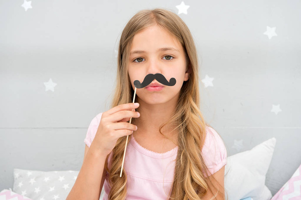 Pajamas party concept. Girl fake mustache at pajamas party. Cheerful kid posing mustache. Photo booth props ideas. Printable accessories for party. Girl long blonde hair posing with photo booth props - Foto, Imagen