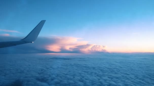 Vleugel van een vliegtuig van een venster boven de wolken van een vliegtuig vliegen bij zonsondergang - Video