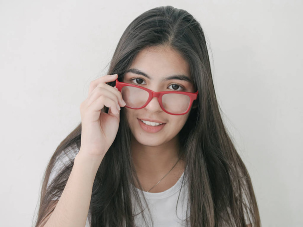 Beautiful Asian teenager girl holding red eyeglasses and look at camera, lifestyle concept. - Foto, afbeelding