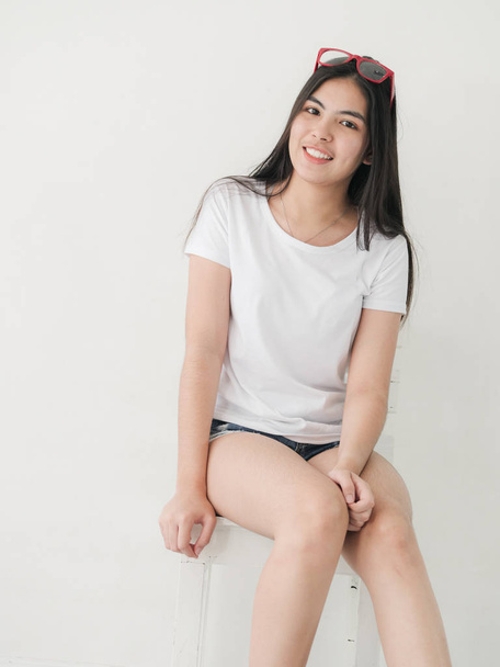 Happy Asian teenager girl sitting on white chair, lifestyle concept. - Photo, image