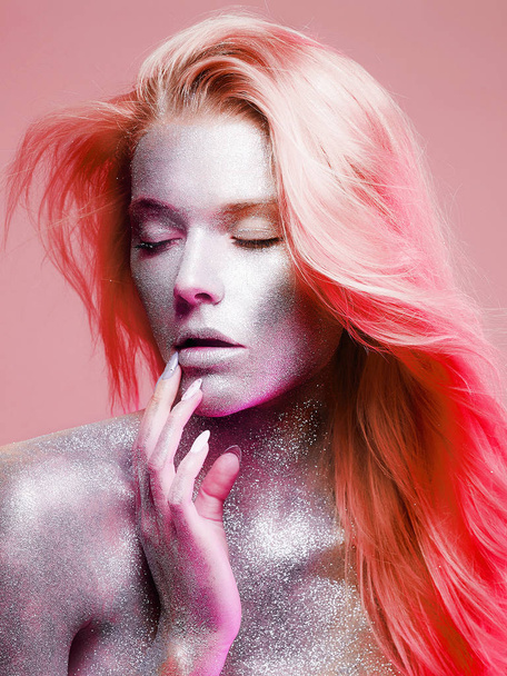 Όμορφη γυναίκα με επιδερμίδα λάμπει σε ροζ χρώμα. Κορίτσι με μακιγιάζ τέχνης σε χρώμα προβολείς - Φωτογραφία, εικόνα