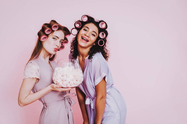 Girls with Marshmallows. Celebrating Women's Day. Emotional Women. Cheerful Women. Beautiful Girl. Girls with Hair Curlers. Marshmellow in Hands. International Women with Hair Curlers. Pink Background - Fotoğraf, Görsel