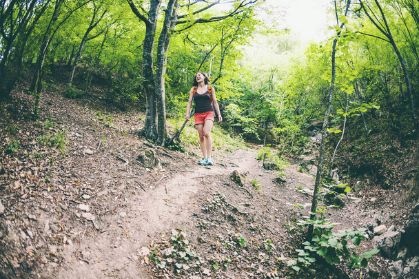 A lány séta az erdőben. Egy fiatal nő, egy hátizsák utazik festői helyeken keresztül. Egy turista séták, hegyi ösvényen. Halszem optika. - Fotó, kép