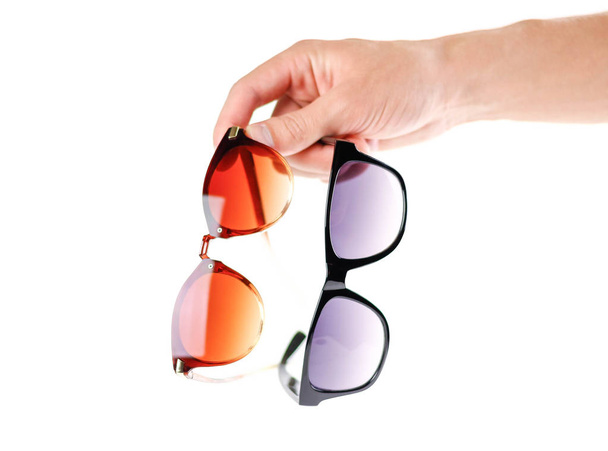 Рука с двумя солнечными очками. Мужские и женские солнечные очки. Закрывай. Изолированный на белом фоне
. - Фото, изображение