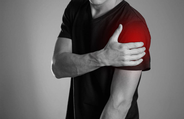A man holding hands. Shoulder pain. The hearth is highlighted in red. Close up. Isolated background. - Photo, Image