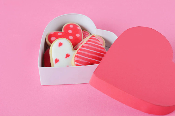Heart shaped cookies decorated for Valentine's Day in red heart shaped box on pink background - Valokuva, kuva