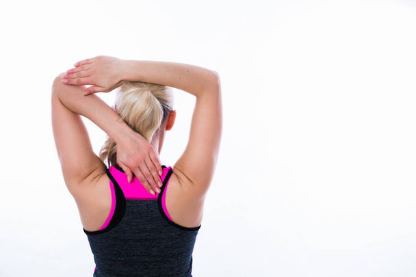 Back view of sporty blonde woman in sport dress who does exercises for arms on white background - Photo, image