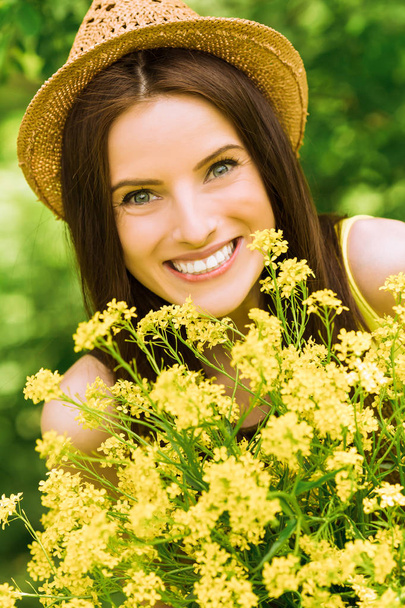 Portrait of young cheerful smiling woman who keeps flowers outdoor - Foto, imagen