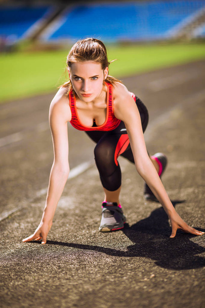 Спортивная ориентированная женщина на старте беговой дорожки готовится к бегу
 - Фото, изображение