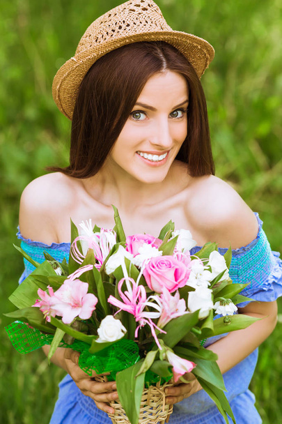 Portrait of young exquisite surprised woman with bare shoulders who keeps bouquet of flowers in hands outdoor - Φωτογραφία, εικόνα