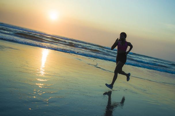 silhouette of young happy and attractive African American runner woman exercising in running fitness workout at beautiful beach jogging and enjoying sunset in health care and outdoors activity  - Foto, Imagen