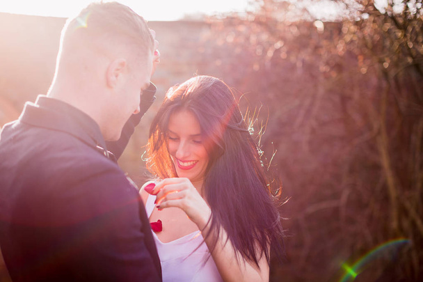 Smiling beautiful couple stands together with the rose petals outdoor - Fotó, kép