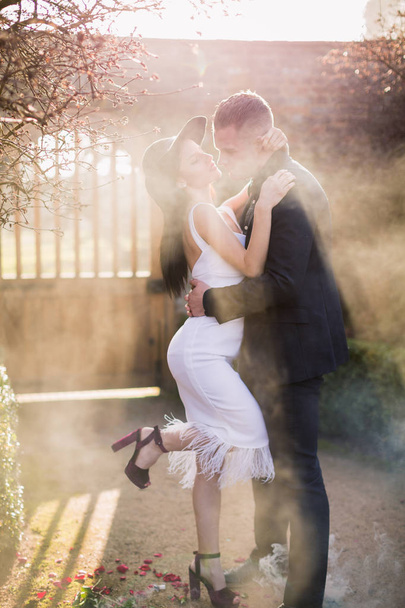 Attractive couple in love stands in the embrace in the yard in the smoke - Fotoğraf, Görsel