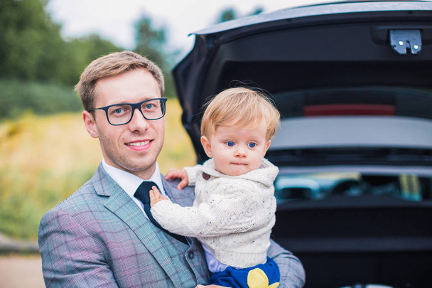 Muotokuva onnellisesta tyylikkäästä isästä, joka pitää pienen pojan auton taustalla
 - Valokuva, kuva