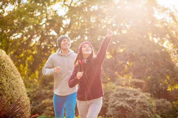 Young happy sporty couple runs in the park on the sunlight and looks up - Foto, Imagem