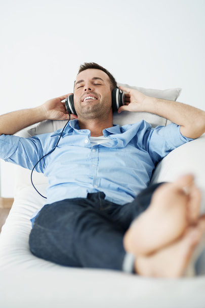 Man wearing headphones lying on the sofa - Valokuva, kuva