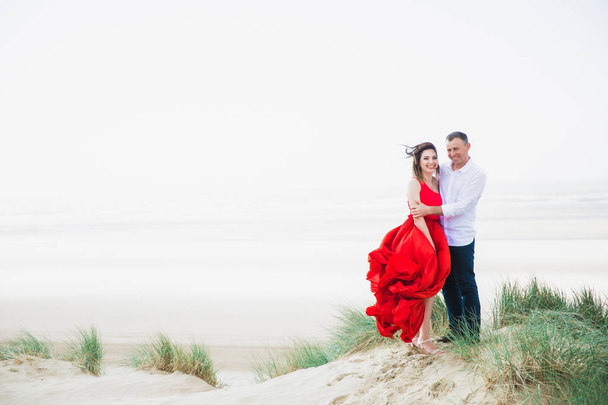 Happy romantic smiling couple stands in embrace against the background of sea - Fotó, kép