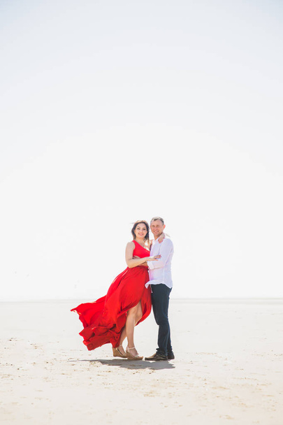 Amazing view of happy romantic couple who stands in embrace on sand - 写真・画像