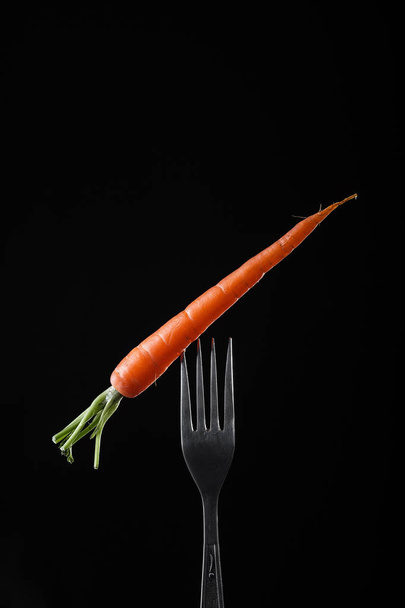 Bunch of carrots on black background.  Vegetables harvest. Organic fresh harvested vegetables - Photo, Image