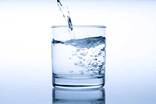 Close up pouring drinking water into glass, studio shot - Zdjęcie, obraz