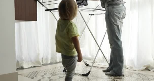 Pequeño niño ayudando a colgar la ropa de su madre
 - Metraje, vídeo