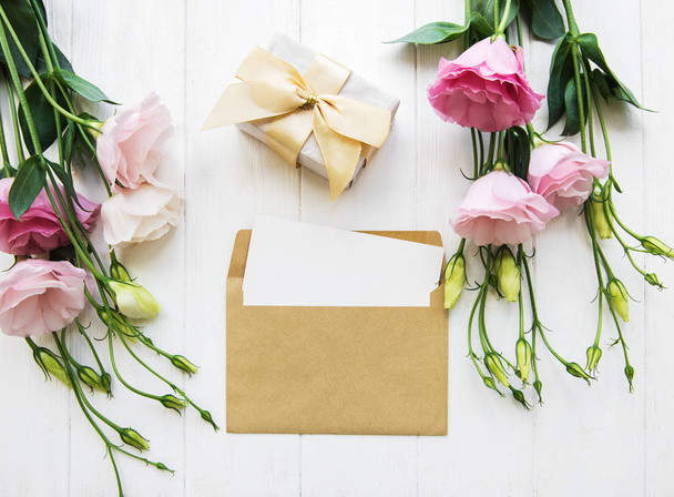 Composição de colocação chata - envelope de carta e um presente com flores rosa
 - Foto, Imagem