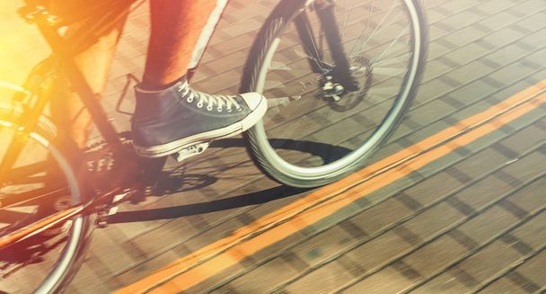 Unrecognizable Cyclist In Sneakers Rides Bicycle Path In Motion Blur Summer Day. Point Of View Shot - Zdjęcie, obraz