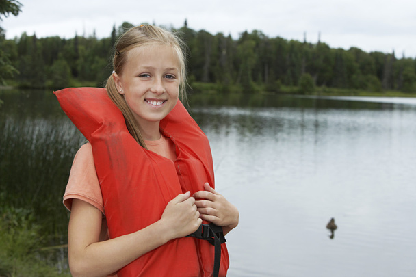 Girl Wearing Life Jacket By Lake - 写真・画像