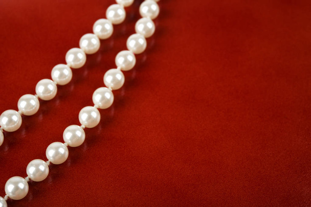 Bílý perlový náhrdelník na načervenalé hnědé pozadí. Selektivní fokus a hloubkou ostrosti. - Fotografie, Obrázek