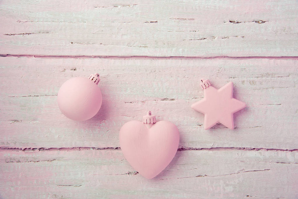 Новогодние рождественские игрушки, сердце, звезда и мяч на красивом деревянном розовом столе
 - Фото, изображение