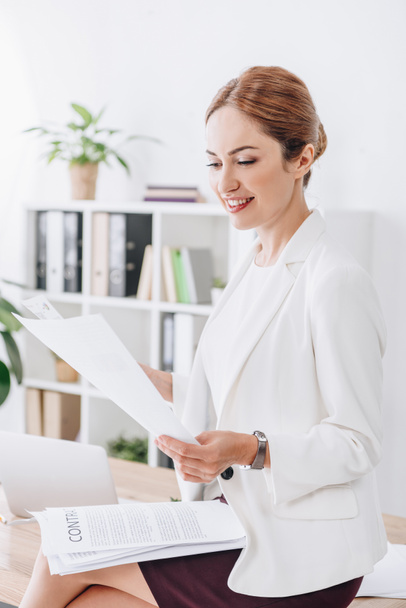 attractive business woman doing paperwork sitting on table in office - Foto, immagini