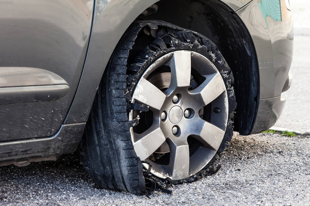 Zničené prasklé pneumatiky s prasklou, roztrhanou a poškozenou gumou na moderním SUV automobilu. Plochá nízkoprofilová pneumatika na kovovém ráfku, roztrhaná na kusy s viditelným interiérem. - Fotografie, Obrázek