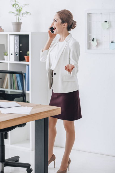 happy professional businesswoman talking on smartphone in modern office - Photo, image