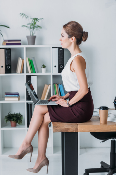 executive serious business woman using laptop while sitting on table in office - Photo, Image
