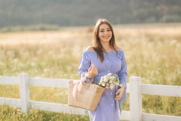 Vue rapprochée de la belle femme enceinte dans le champ tenant bouquet et sourire. Détendez-vous dans la nature
 - Photo, image