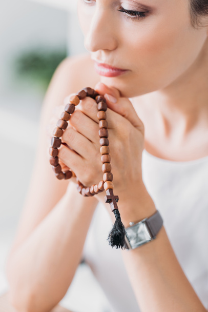 beautiful female prayer holding wooden rosary beads - Photo, Image
