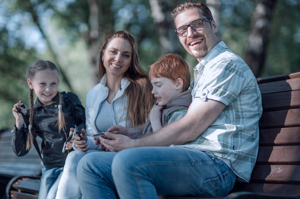 happy family sitting on bench in summer Park - Valokuva, kuva
