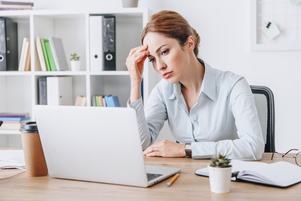 exhausted adult businesswoman with headache touching her head while sitting at office - Photo, Image