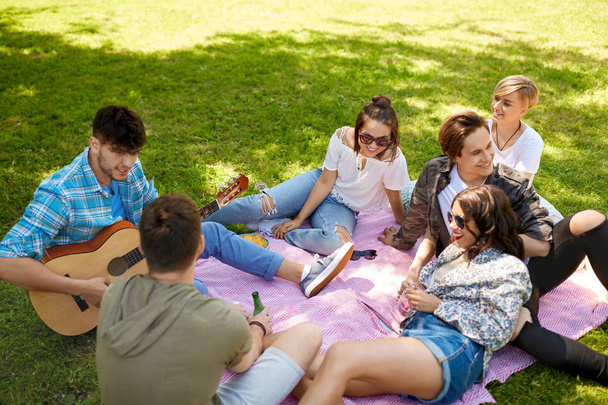 friends playing guitar at picnic in summer park - Valokuva, kuva