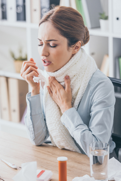 adult sick businesswoman with cough sitting at workplace in scarf - Фото, изображение