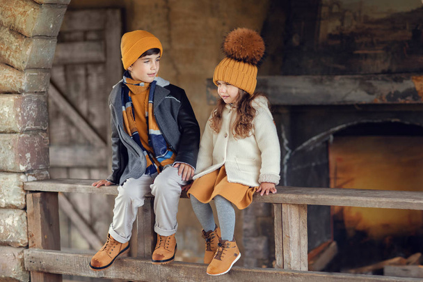 boy and girl sitting on the wooden railing of old house together - Photo, Image