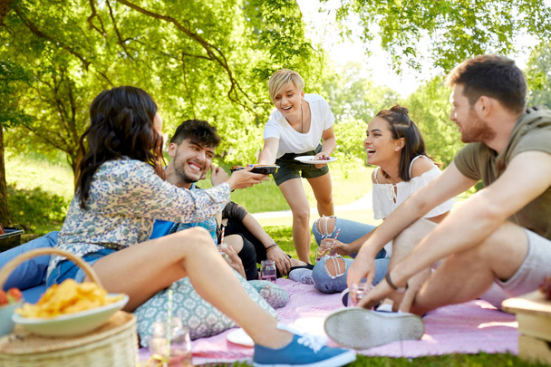 friends with drinks and food at picnic in park - Foto, imagen