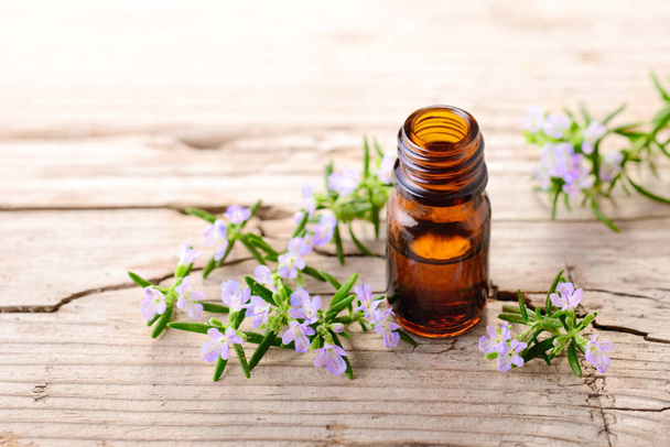 rosemary essential oil and flowers on the wooden board - Foto, Imagen