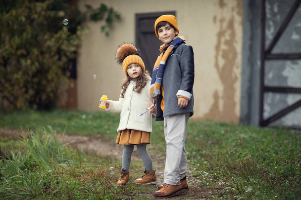 full length shot of sister with soap bubbles bottle and brother standing outdoors  - Fotografie, Obrázek