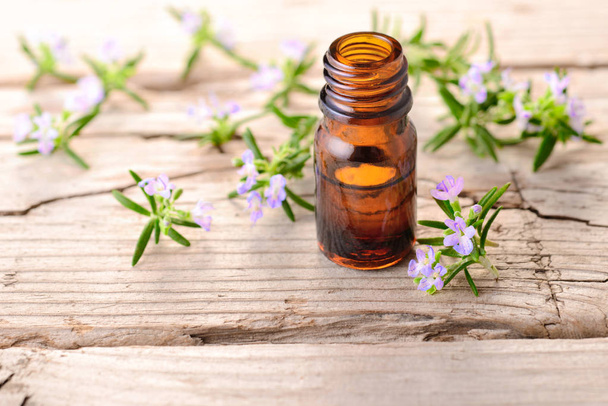 masážní olej rozmarýn a květiny na dřevěné desce - Fotografie, Obrázek