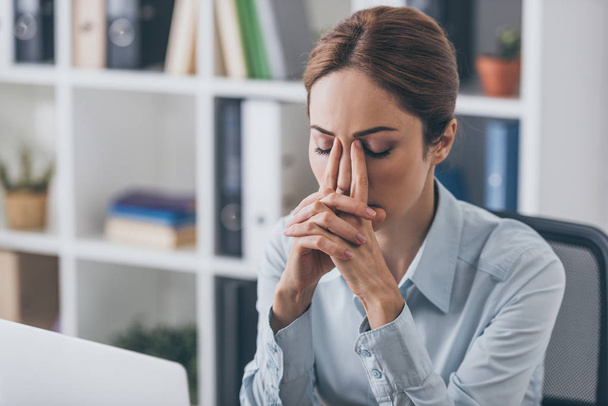 depressed adult businesswoman sitting with closed eyes at office - Foto, Bild