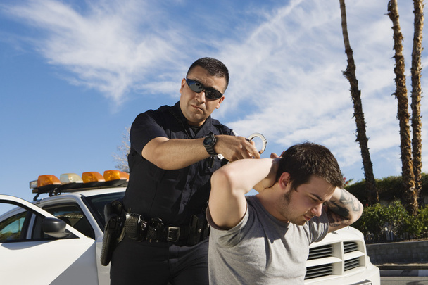 Police Officer Arresting Young Man - 写真・画像